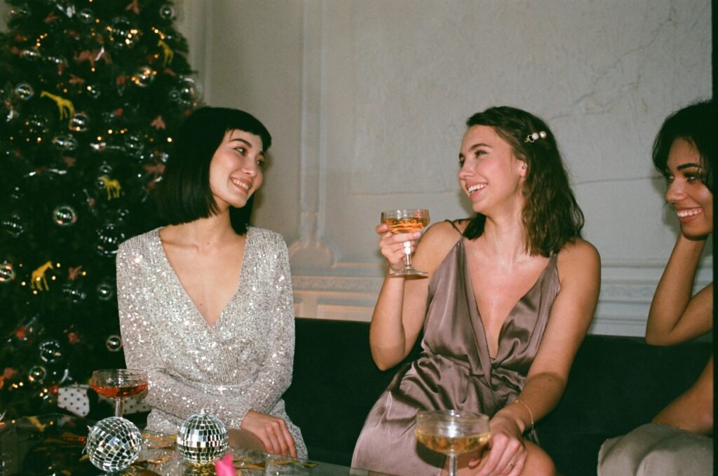 Three women enjoying festive celebration indoors with cocktails and joy.